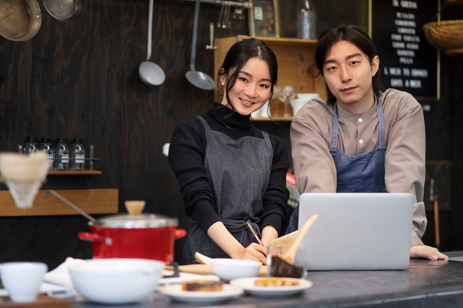 ノートパソコンの前に立つ小さなカフェのオーナー夫婦
